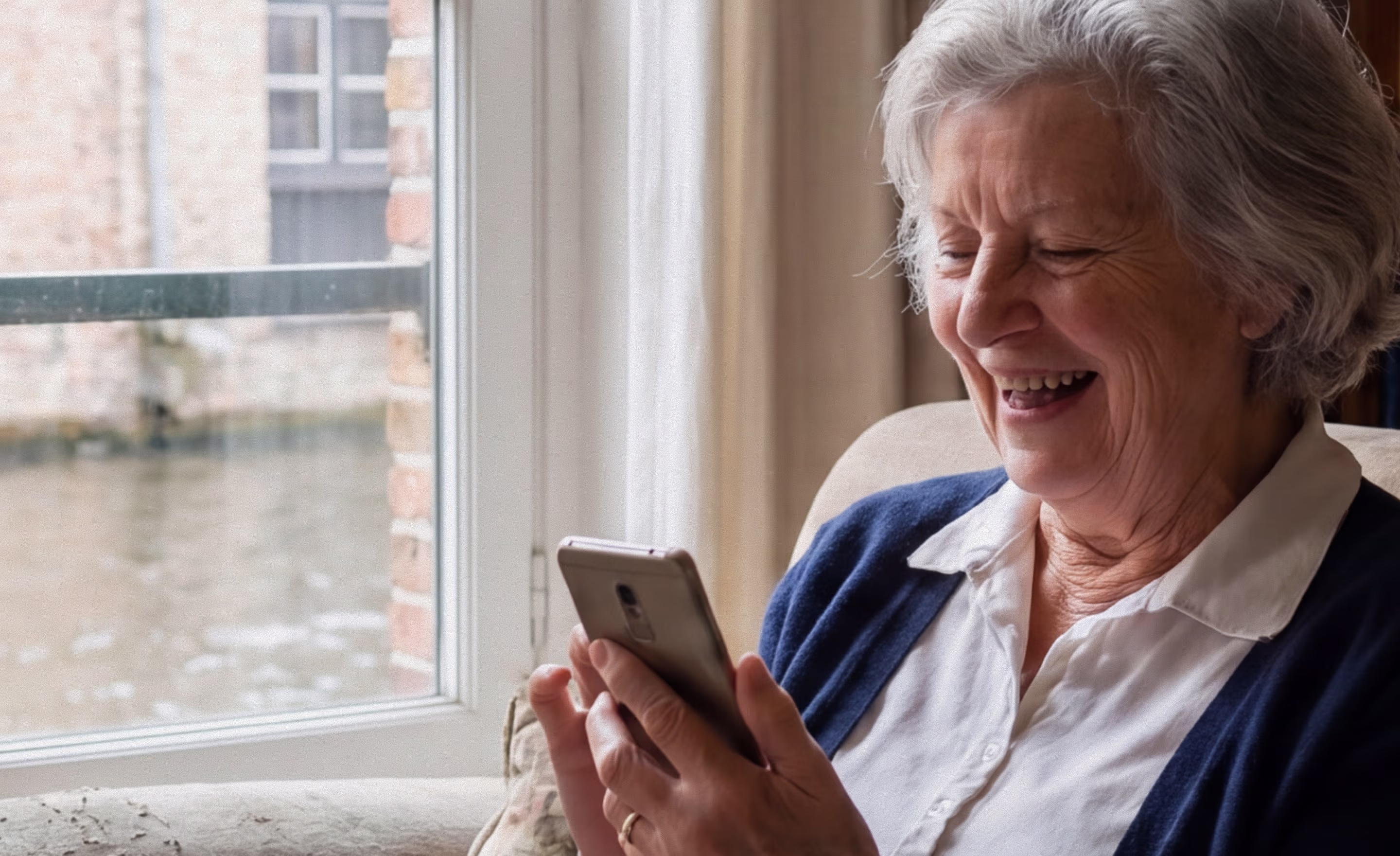 Smiling elderly woman sitting in an armchair, looking at her phone